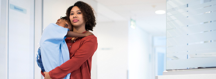 Mother holding her child in a hospital corridor waiting for discharge instructions after a hospital visit